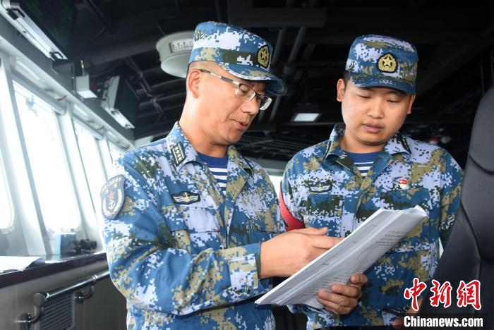Zhou Minghui (left), the captain of the Nanchang ship, communicated with the officers and soldiers on duty in the cockpit.Photo by China News Agency reporter Sun Zifa