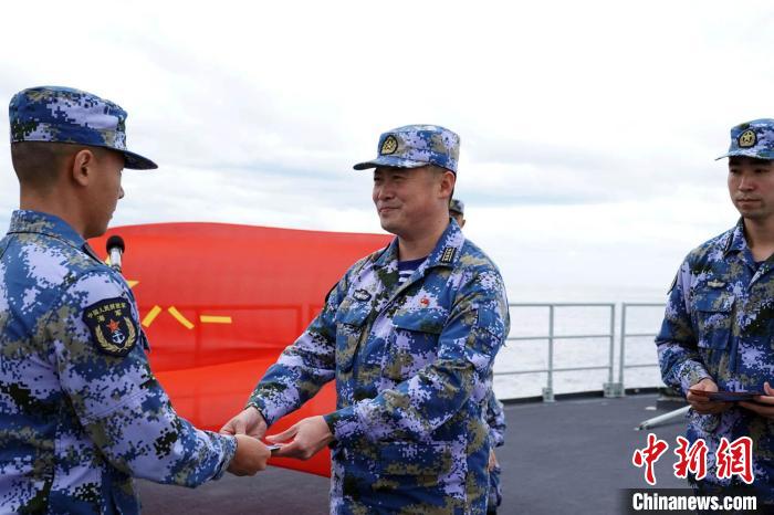 Chen Weigong, political commissar of the Nanchang ship, awarded a commemorative card to the newly boarded officers and soldiers.Photograph by Sun Jingang