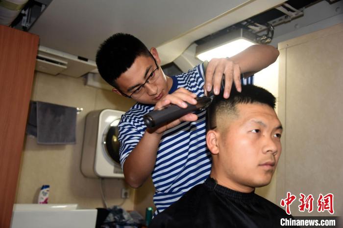 Part-time barbers of the officers and soldiers of the Nanchang ship provide haircuts for their comrades.Photo by China News Agency reporter Sun Zifa